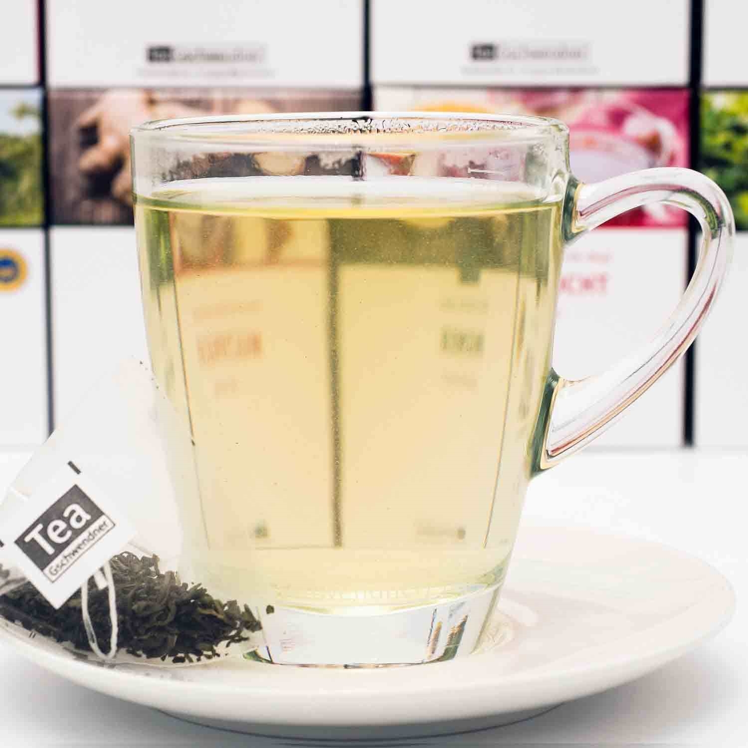 Transparente Tasse mit grünem Tee und Teebeutel, tee, kräutertee, glasbecher, heißgetränk, lose blätter tee