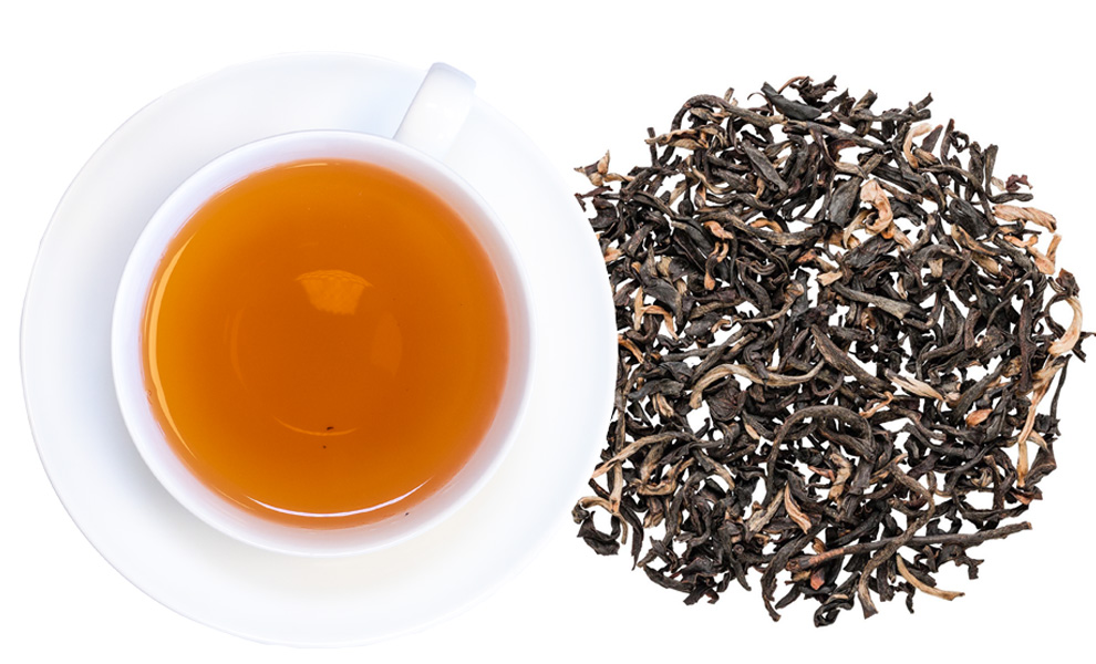Weiße Tasse mit schwarzem Tee und losem Schwarztee