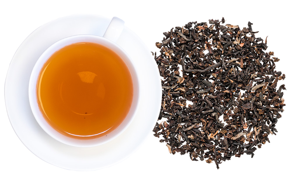 Weiße Tasse mit schwarzem Tee und losem Blatttee