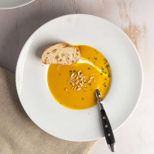 Plate of pumpkin soup with bread and pine nuts