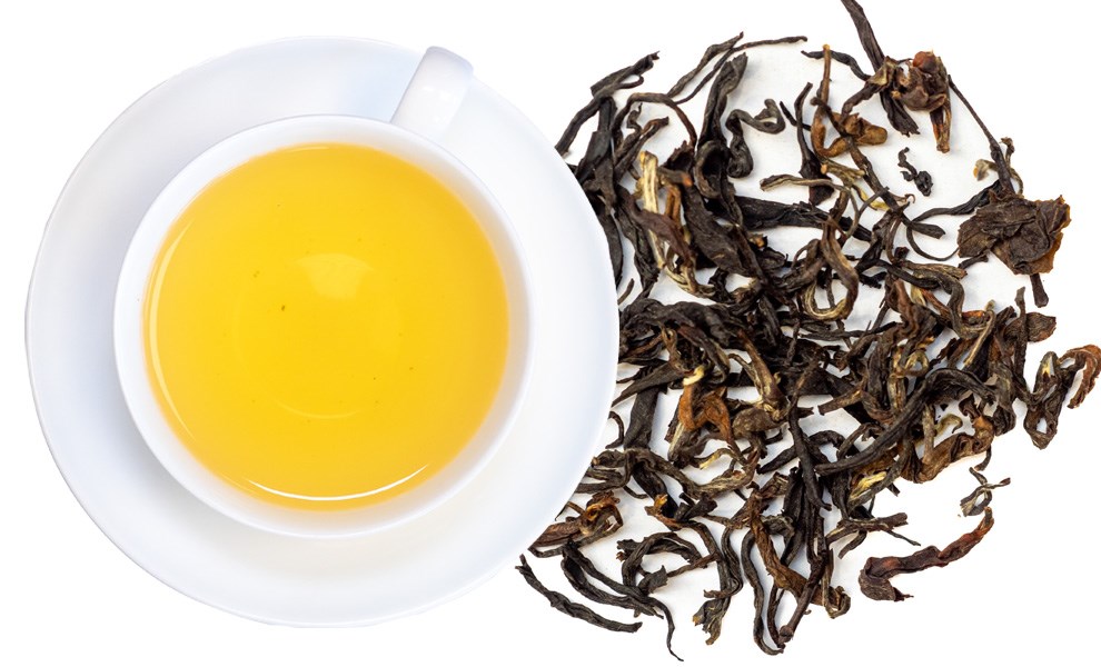 Weiße Tasse Oolong-Tee neben losen Teeblättern, tee, tee-blätter, goldenes tee, tasse, aufguss