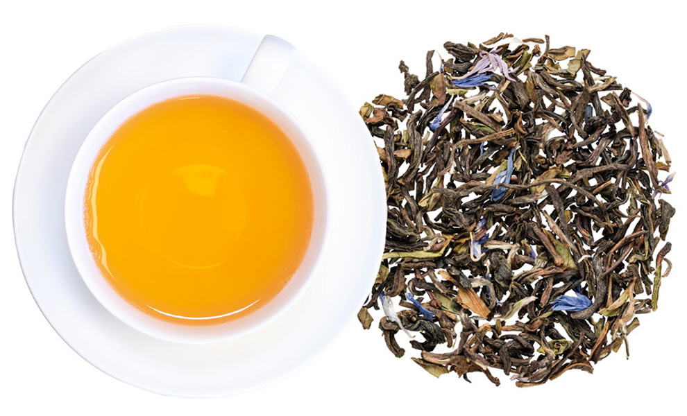 Weiße Tasse Tee mit losem Blatttee daneben