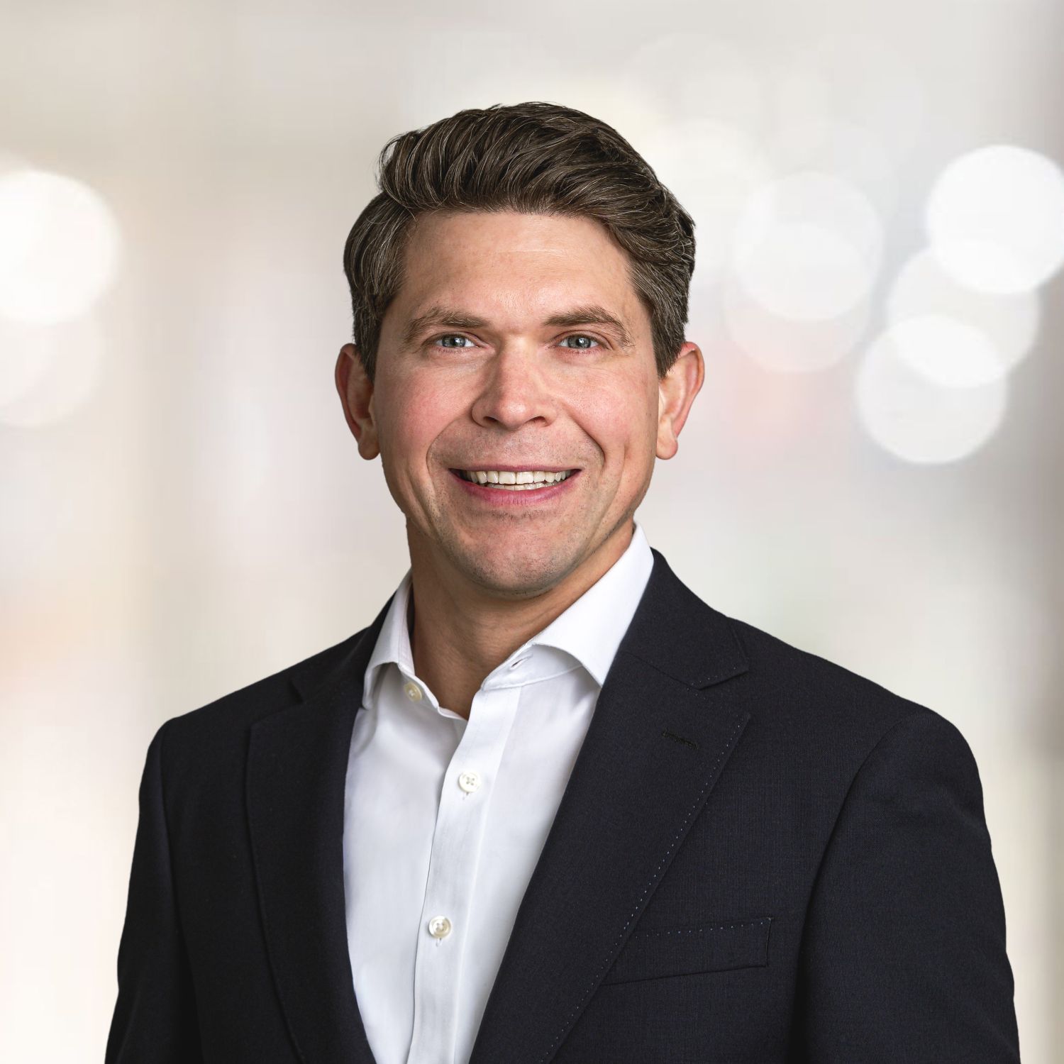 Lächelnder Mann im Business-Anzug vor hellem Hintergrund