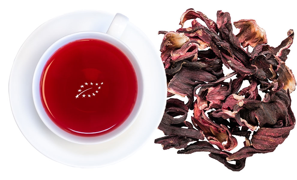Rote Tasse Hibiskustee neben getrockneten Hibiskusblüten, tee, tasse, hibiskus, rotertee, getraenkepulver