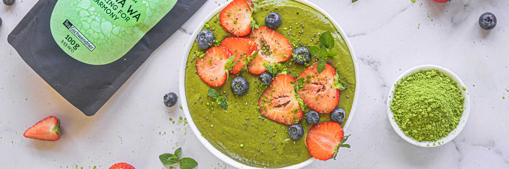 Matcha Bowl mit frischen Erdbeeren und Blaubeeren auf Marmor