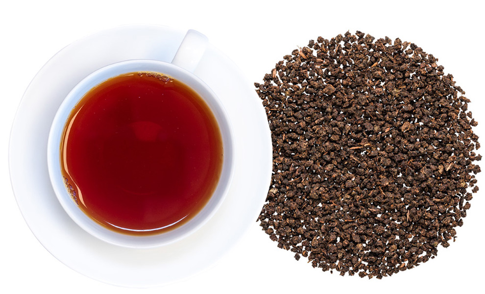 Weiße Tasse Schwarztee neben losen Teeblättern