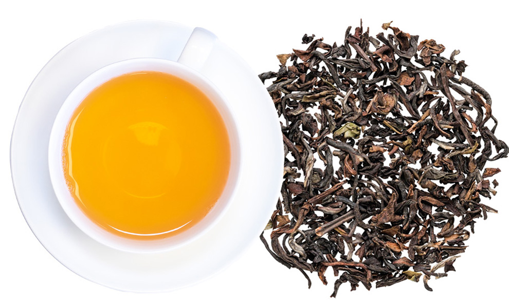 Weiße Teetasse mit schwarzem Tee und losen Teeblättern